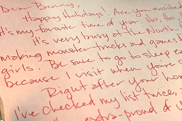 Macro photo of a handwritten letter from Santa in red ink, beginning Dear Benny, Happy Holidays