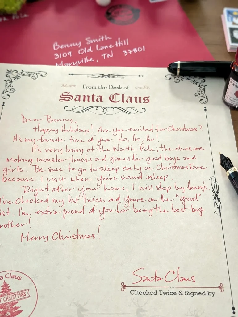 A handwritten letter from Santa in red ink on North Pole letterhead, signed by Santa Claus