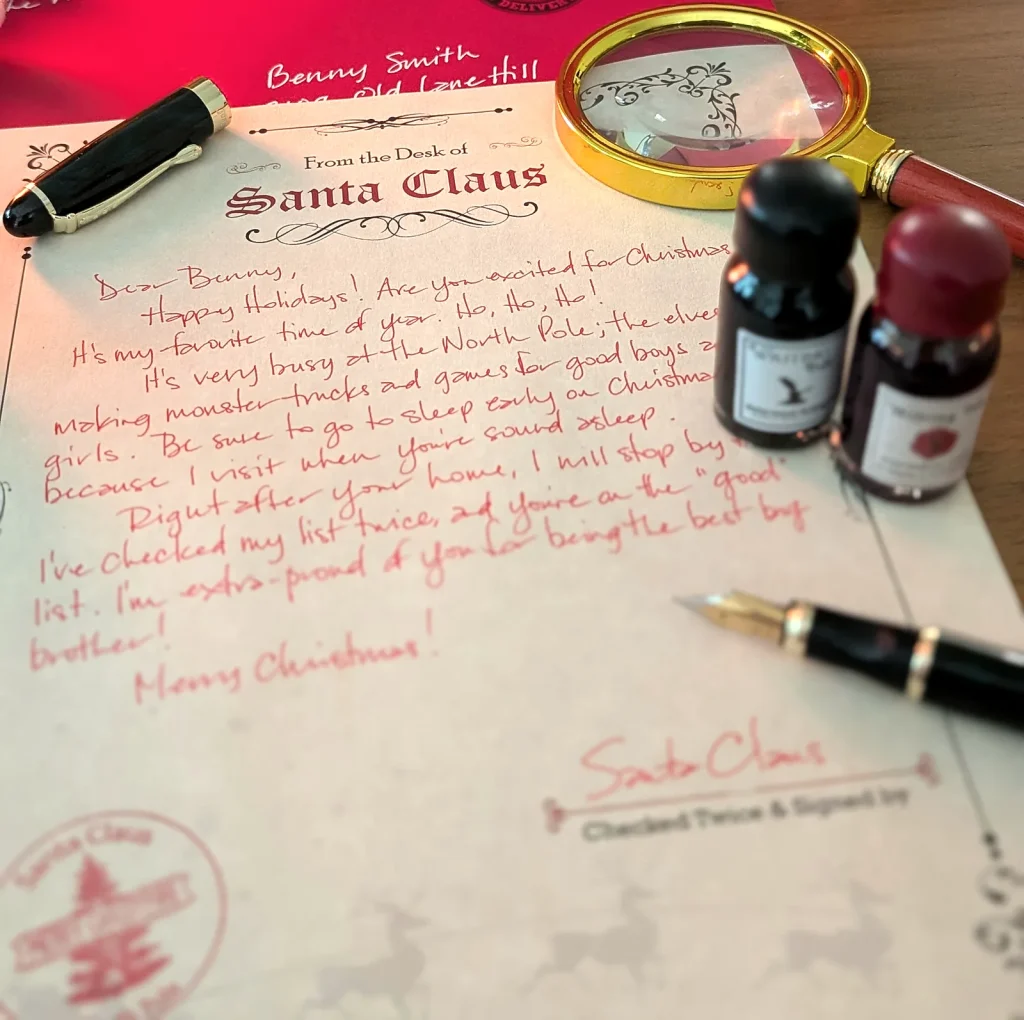 A real handwritten letter from Santa in red ink, the fountain pen resting on it