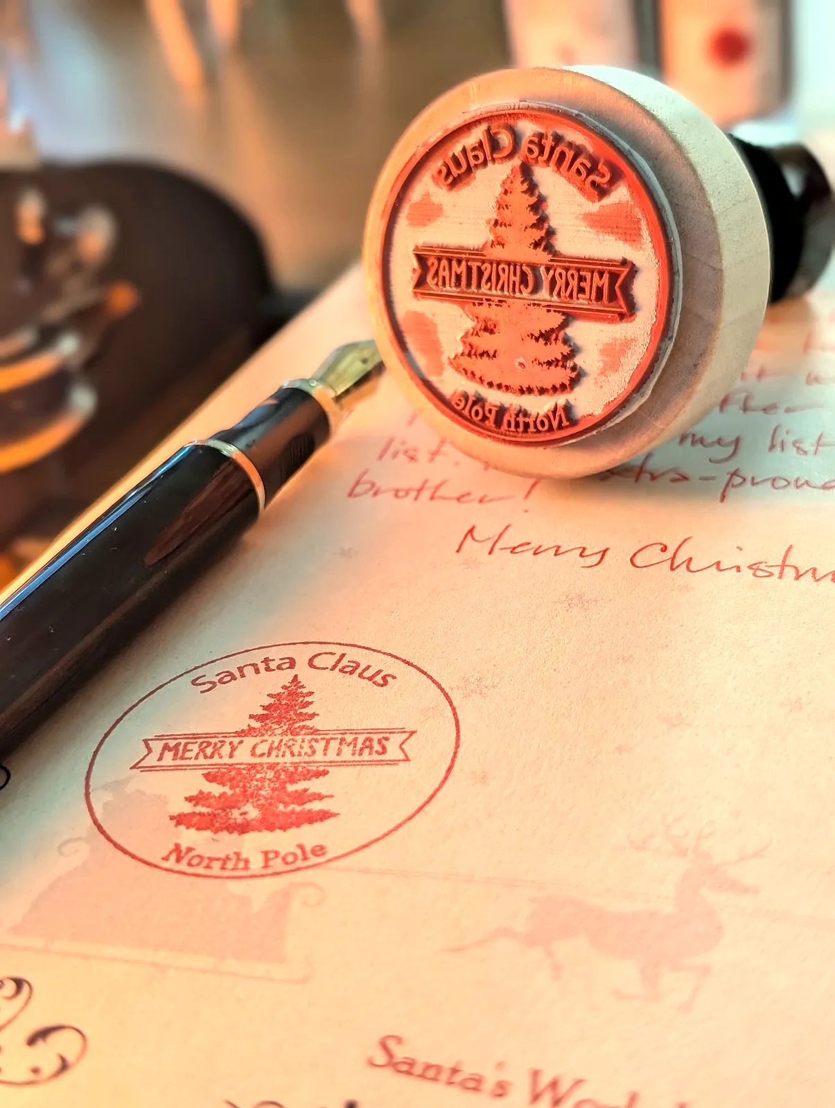 The red Santa Claus North Pole stamp pressed on the letter, the rubber stamp and the pen beside it