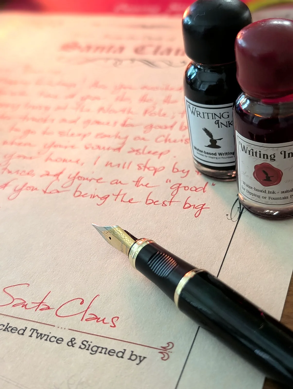 Red ink handwriting on the Santa letter with the fountain pen nib and the writing ink bottles